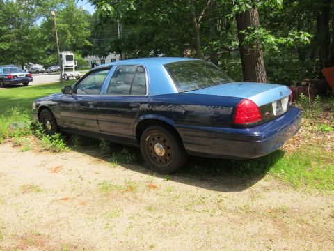 2001 Ford Crown Victoria - A dark blue and light blue 2001 Ford Crown Victoria sedan is parked outdoors next to a grassy area, with another vehicle visible in the bac…