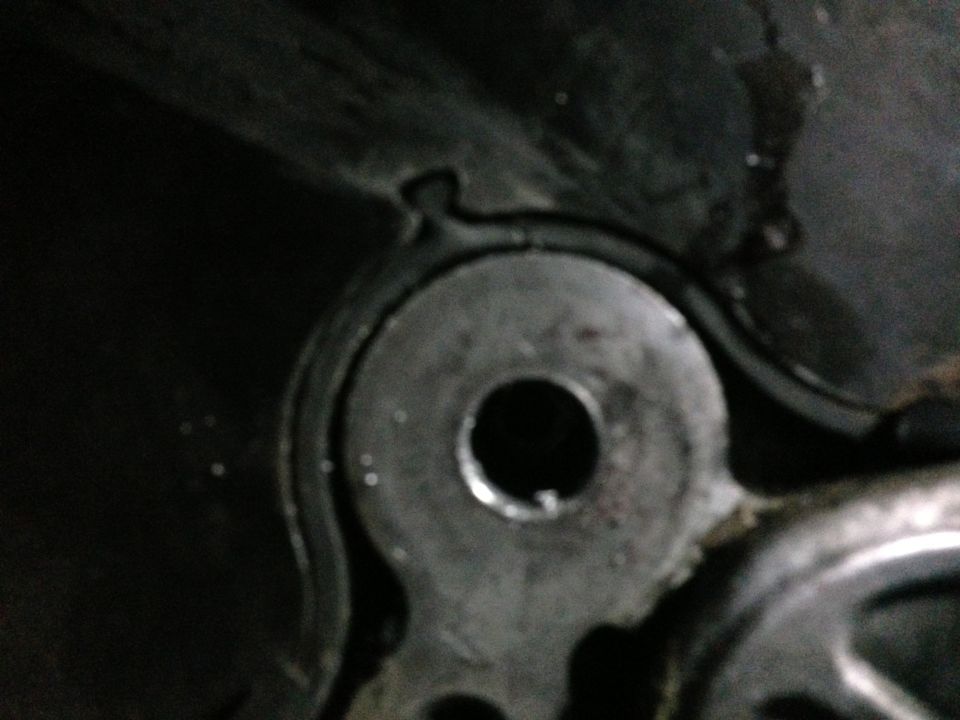 Close-up of a metal engine component with a circular hole, showing wear and grease