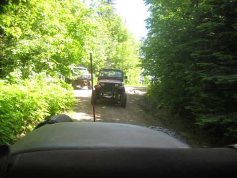 2005 Jeep Wrangler - Two Jeep Wranglers on a dirt road, one following the other through a wooded area.