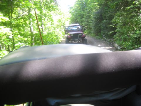 2005 Jeep Wrangler - Two Jeep Wranglers drive down a dusty, tree-lined dirt road.