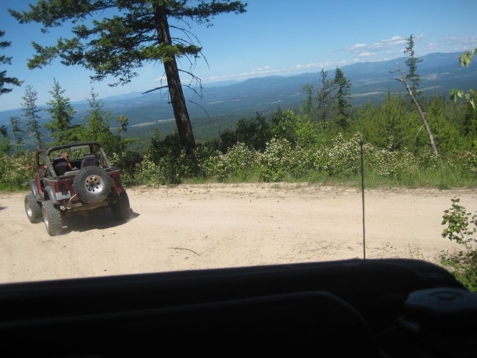 Red 2005 Jeep Wrangler parked on a dirt road overlooking a valley