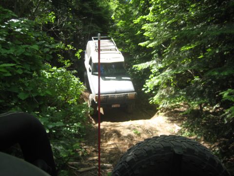 2005 Jeep Wrangler - SUV navigates a wooded trail, with another vehicle's tire visible in the foreground.