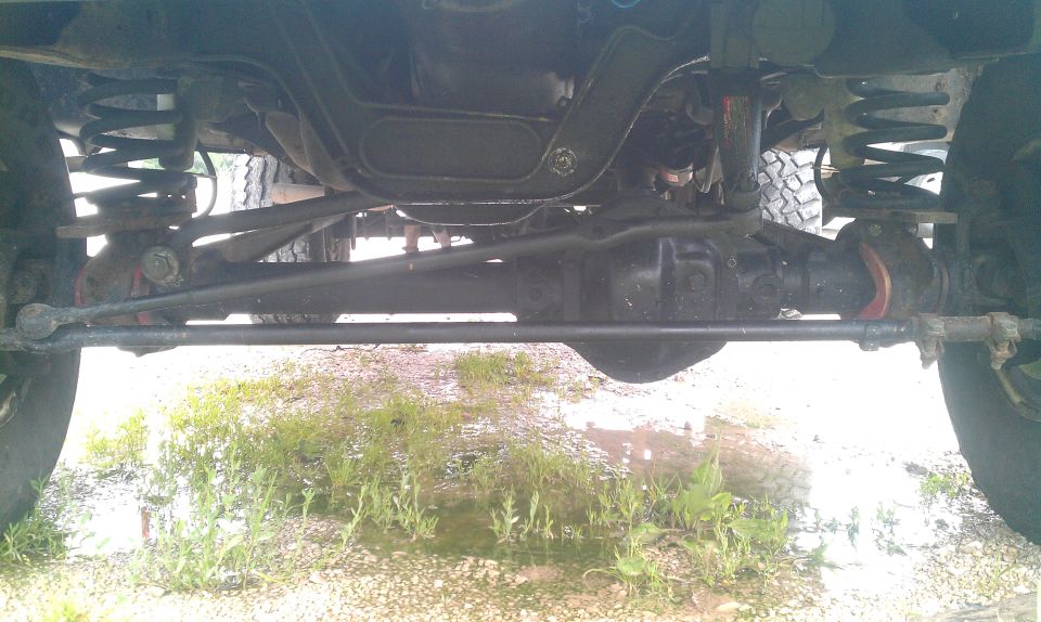 Undercarriage view showing front axle, suspension components, and steering linkage of a 4x4 vehicle