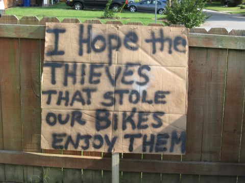 1994 Ford Bronco - A handmade sign expresses a sentiment about stolen bicycles, with vehicles visible in the background.