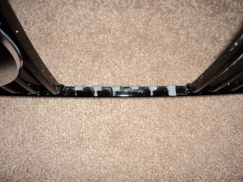 2004 Mercury Grand Marquis - Close-up of a black grille with chrome accents and grey mounting clips, identified as a part from a 2004 Mercury Grand Marquis.
