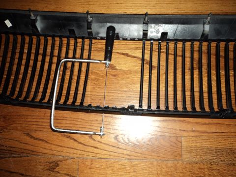 2004 Mercury Grand Marquis - A car grille is shown with a hacksaw, suggesting modification or repair.