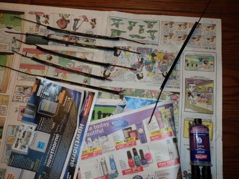 2004 Mercury Grand Marquis - Car parts, including windshield wiper blades, laid out on newspaper advertisements with a bottle of epoxy.