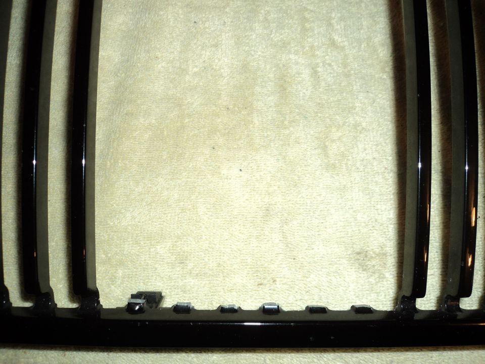 Black grille with vertical slats and mounting clips visible