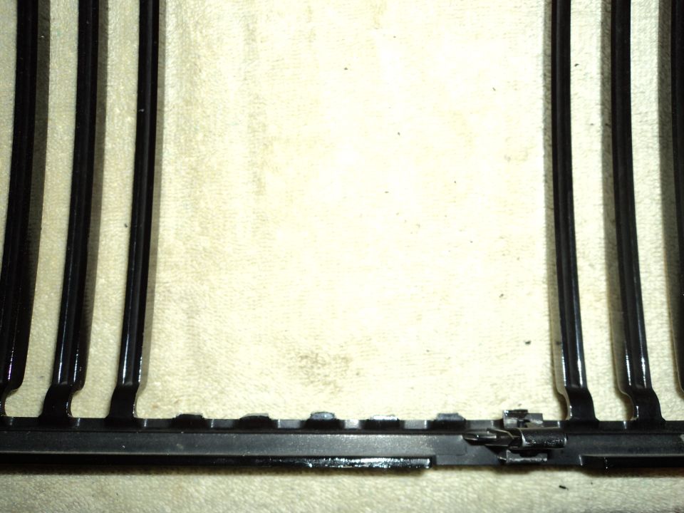 Black car grille with vertical bars and a metal latch mechanism