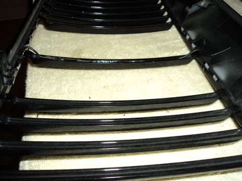 2004 Mercury Grand Marquis - Close-up of a black horizontal bar grille, likely a car part, resting on a textured surface.