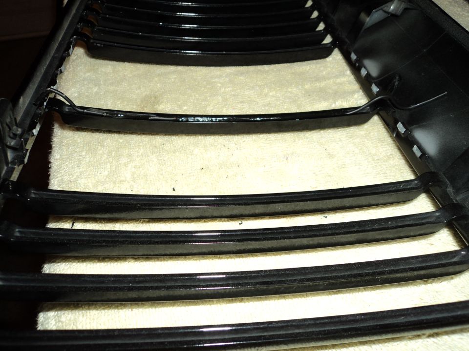 Black horizontal bar grille, possibly for a car, on a textured surface