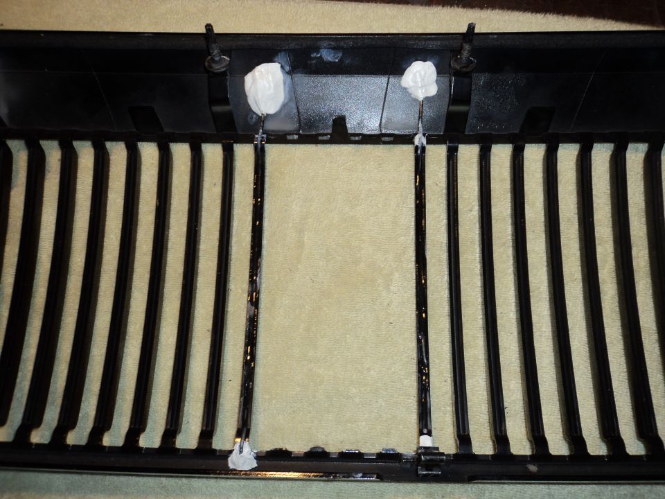 black car grille with vertical bars, some white adhesive visible