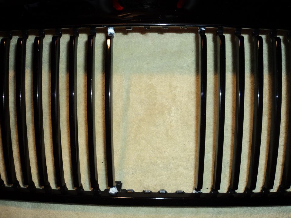 Black vertical bar grille with chrome trim, some mounting tabs visible