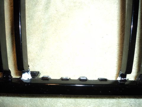 2004 Mercury Grand Marquis - Close-up of a black-finished grille or trim panel showing mounting clips and tabs, resting on a tan cloth.