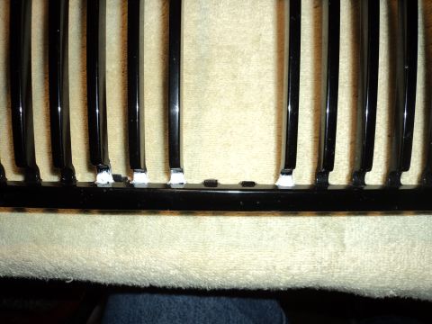 2004 Mercury Grand Marquis - A black car grille is shown with white adhesive applied to the lower mounting points of the vertical slats.