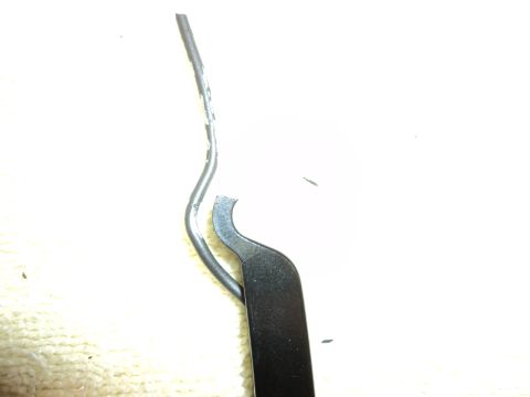 2004 Mercury Grand Marquis - A close-up view of a damaged metal trim piece with a wire nearby.