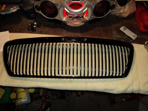 2004 Mercury Grand Marquis - A black grille with vertical slats is laid out on a towel, with a car stereo and remote visible above.