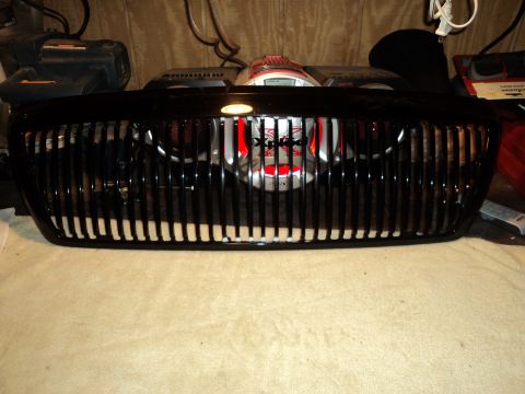 2004 Mercury Grand Marquis - A black vertical grille is shown, possibly for a car, with some red and silver object visible behind it.