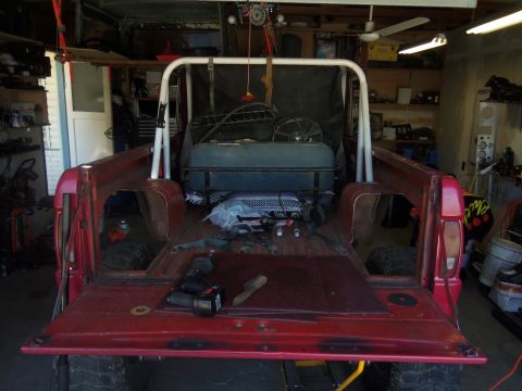 1968 Ford Bronco - Rear view of a 1968 Ford Bronco pickup truck bed, showing a roll cage and tailgate down inside a garage.