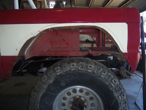 1968 Ford Bronco - Side view of a 1968 Ford Bronco fender undergoing modification, with a large off-road tire visible.