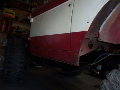 1968 Ford Bronco - The side of a vehicle with a two-tone paint job is visible, along with a large off-road tire and suspension components.