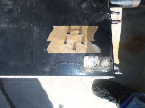1968 Ford Bronco - Close-up view of a black vehicle panel showing a repair with tape and bolts, along with some sealant.
