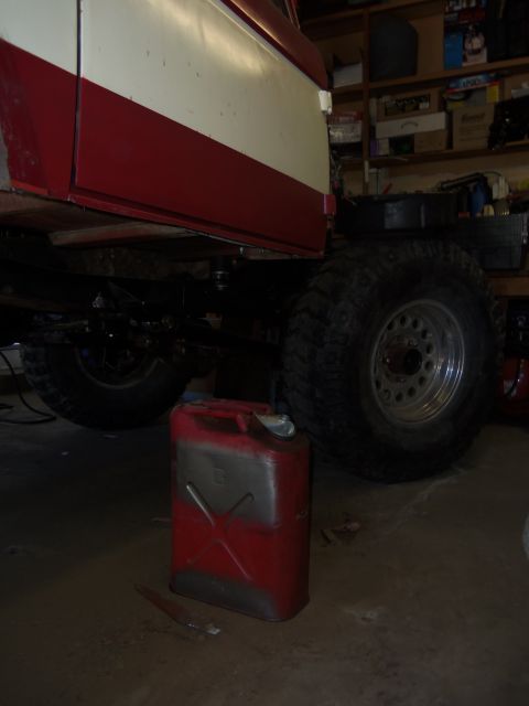 1968 Ford Bronco - A red and white vehicle is shown from underneath, with a red jerrycan placed nearby on the garage floor.