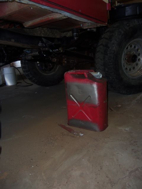 1968 Ford Bronco - A red jerry can sits on the floor near the undercarriage and large tire of a vehicle.
