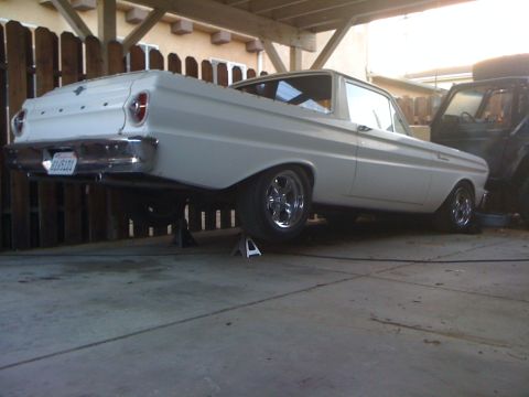 1964 Ford Ranchero - Rear view of a white 1964 Ford Ranchero pickup truck, elevated on jack stands in a garage.