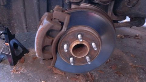 2003 Mercury Marauder - A close-up view of a car's brake rotor and caliper, with a jack stand visible to the left.