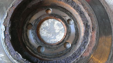 2003 Mercury Marauder - This severely worn brake rotor shows extensive rust and damage, indicating a need for replacement.