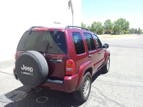 2005 Chevrolet Venture - A red Jeep Liberty is parked outdoors, showing its rear and side profile with a spare tire cover.