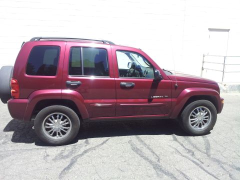 2005 Chevrolet Venture - Side view of a red Jeep Liberty SUV, a spare tire mounted on the rear door.