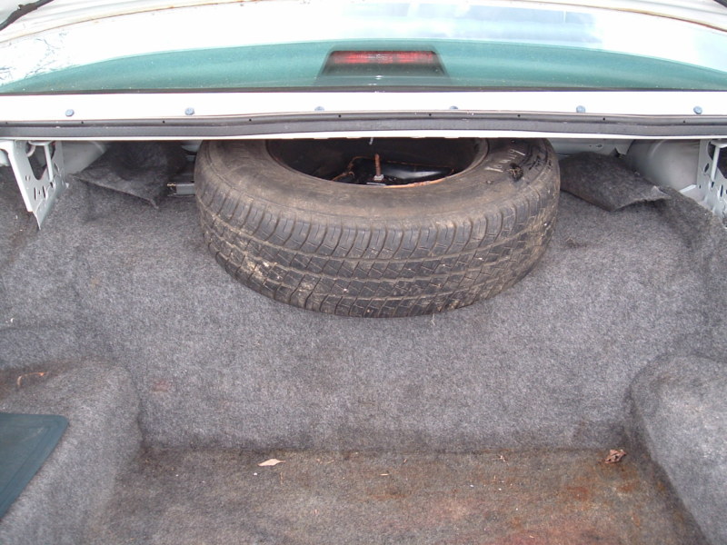 Trunk interior of a 1991 Ford Crown Victoria LTD showing the spare tire and carpet lining