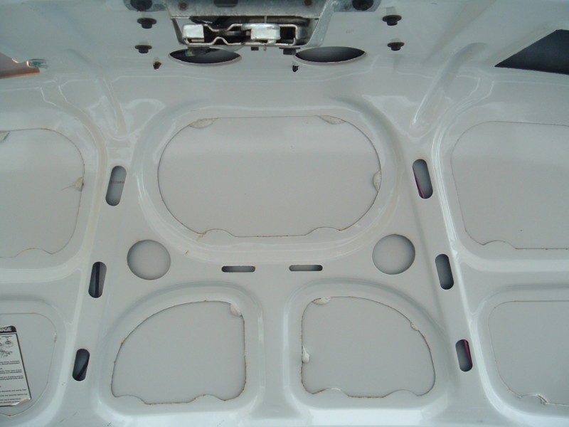Underside of white car hood with latch mechanism visible at top. Shows bracing and insulation