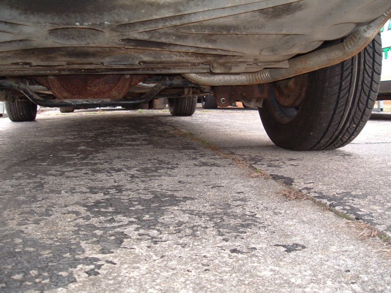 Underside view of a car, showing the exhaust pipe, suspension components, and tires