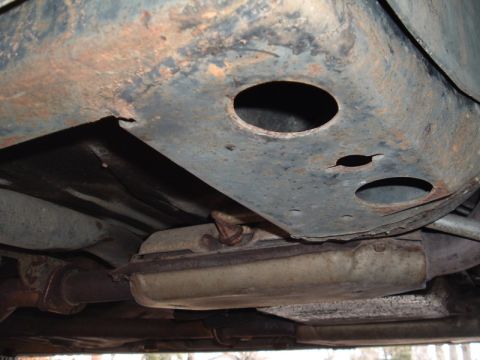 1991 Ford LTD Crown Victoria - The underside of a vehicle shows extensive rust and corrosion on the frame and exhaust system.
