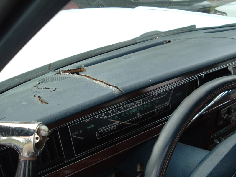 Damaged dashboard with cracked vinyl and a partial view of the steering wheel and instrument cluster