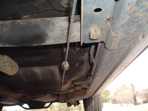 1991 Ford LTD Crown Victoria - The underside of a vehicle reveals its fuel tank, exhaust, and frame components, showing signs of rust.