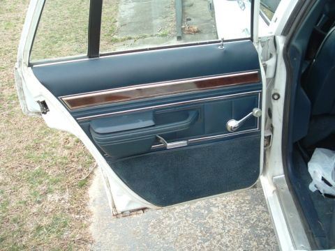 1991 Ford LTD Crown Victoria - Close-up of a car's interior door panel with blue fabric and chrome accents.