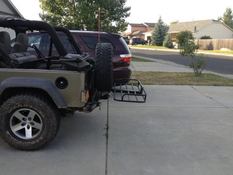 2005 Jeep Wrangler - A Jeep Wrangler is parked in a driveway with a hitch carrier attached to the rear bumper.