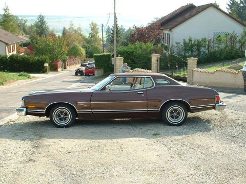 1991 Ford LTD Crown Victoria - Side view of a brown 1977 Ford Thunderbird coupe parked on a gravel lot.