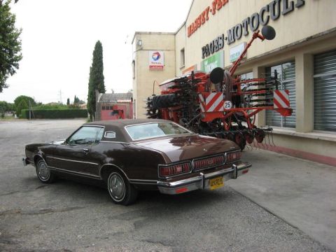 1991 Ford LTD Crown Victoria - A classic Ford Thunderbird is parked in front of a dealership agricultural machinery.
