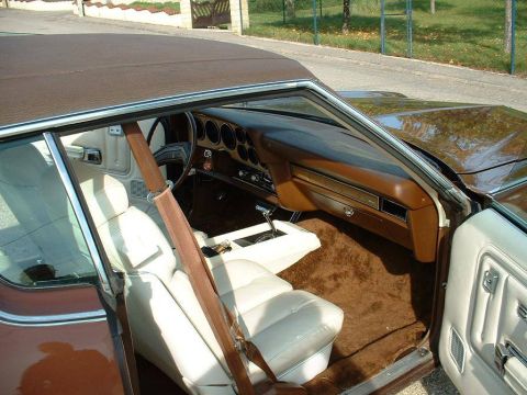1991 Ford LTD Crown Victoria - The interior of a classic coupe features white seats and a brown dashboard with wood-grain accents, along with a visible website address fo…