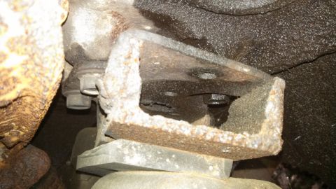 1979 Ford Bronco - Undercarriage view shows a heavily rusted metal bracket and bolt assembly.