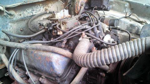1979 Ford Bronco - Close-up view of a dirty engine bay with various components and hoses.