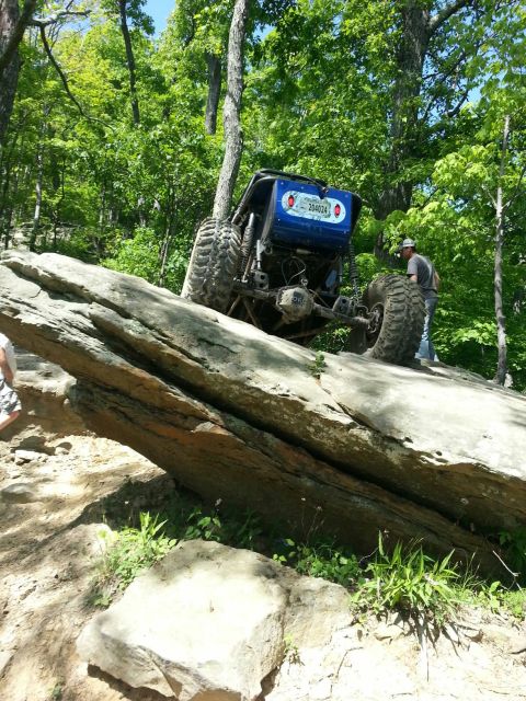 1967 Ford Mustang - A custom blue off-road buggy navigates a steep rock obstacle on a wooded trail.