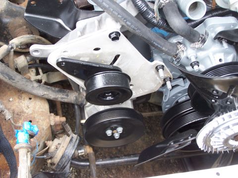 1991 Ford LTD Crown Victoria - Close-up view of engine components, including pulleys and hoses, with some text visible on a hose.