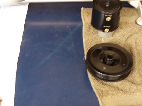 1991 Ford LTD Crown Victoria - A black pulley and air filter housing are displayed on a towel, likely for automotive repair or parts identification.
