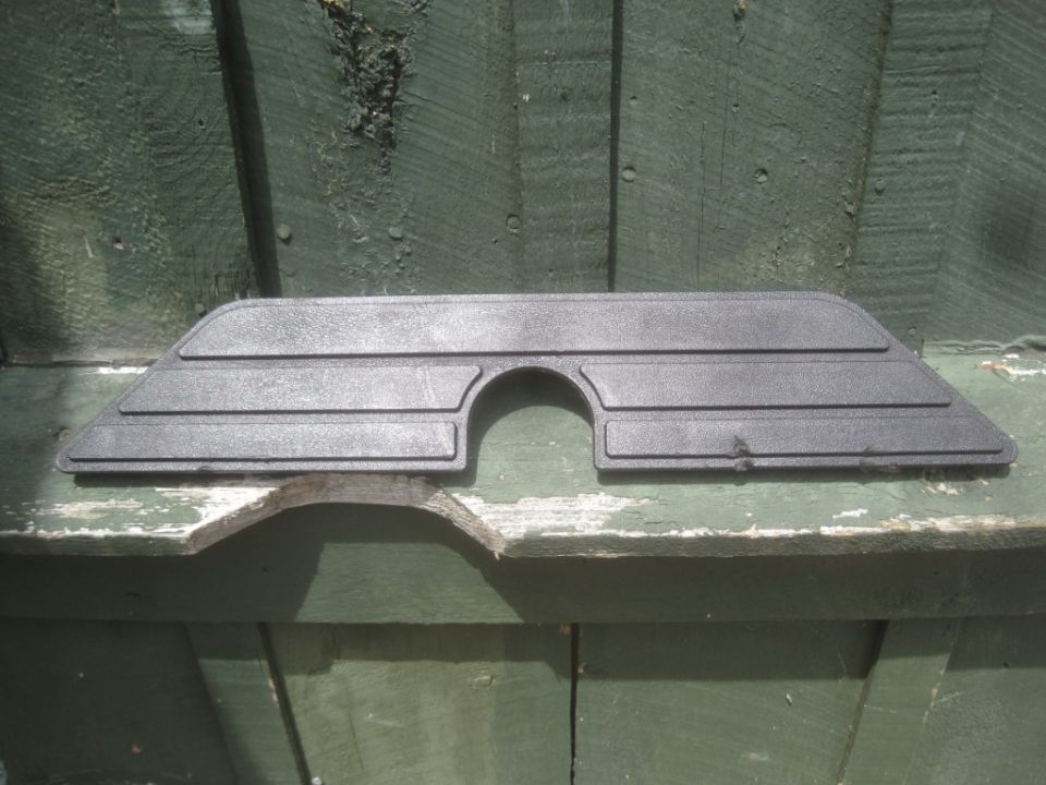 Dark gray plastic interior trim piece with semicircular cutout